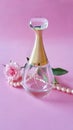 Beautiful perfume bottle, pearl necklace and rose flower on pink background