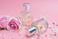 Beautiful perfume bottles and rose on pink