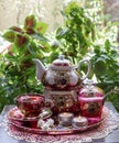 Beautiful Persian tea set and lit candles on the table with green plants on the background Royalty Free Stock Photo