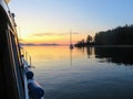 A beautiful perspective from a boat of a remote bay with one sailboat anchored as the sunsets over the horizon of the ocean Royalty Free Stock Photo