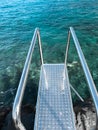 Beautiful image of metail handsrails and stairs going in blue ocean water Royalty Free Stock Photo