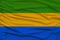 Beautiful photo of the national flag of Gabon on delicate shiny silk with soft draperies, the concept of state power, country life