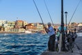 Beautiful photo of old man fishing in harbor with other fishermen in background.