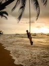 Beautiful image of sexy yougn woman in swimsuit swinging on the rope tied to the palm tree over the ocean beach Royalty Free Stock Photo