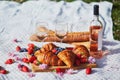 Beautiful picnic with rose wine, French croissants and fresh berries