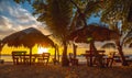 Beautiful picture of beach cabanas and palms against a mesmerizing orange sunset in  Roatan Royalty Free Stock Photo