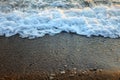 A beautiful picture of a sea wave with foam running onto the beach in the rays of the setting sun. Sea waves at sunset Royalty Free Stock Photo