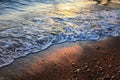 A beautiful picture of a sea wave with foam running onto the beach in the rays of the setting sun. Sea waves at sunset Royalty Free Stock Photo