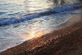 A beautiful picture of a sea wave with foam running onto the beach in the rays of the setting sun. Sea waves at sunset Royalty Free Stock Photo