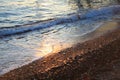 A beautiful picture of a sea wave with foam running onto the beach in the rays of the setting sun. Sea waves at sunset Royalty Free Stock Photo