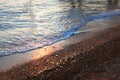 A beautiful picture of a sea wave with foam running onto the beach in the rays of the setting sun. Sea waves at sunset Royalty Free Stock Photo