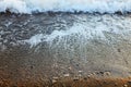 A beautiful picture of a sea wave with foam running onto the beach in the rays of the setting sun. Sea waves at sunset Royalty Free Stock Photo