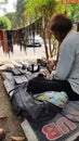 An unknown Shoe Cobler Repairing a Pair of Shoes at Indian Street.