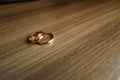 Beautiful picture with wedding rings lie on a wooden surface against the background of a bouquet of flowers Royalty Free Stock Photo