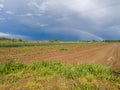 A beautiful picturesque scenic landscape of arable agricultural land after the rain and a colorful rainbow in the background Royalty Free Stock Photo