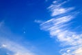 Beautiful picturesque white feather clouds against the blue sky with a young moon , magic romantic background