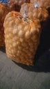 Beautiful pile of fresh potatoes in orange transparent bag on tile floor