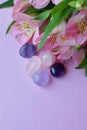 Beautiful pink alstroemeria flowers and semi-precious stones rose quartz and amethyst lie on a pink background. Copy space