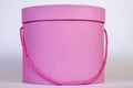 A beautiful pink circular gift box for packing a surprise inside with a closed lid and a cord instead of a ribbon close-up on a