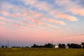 Beautiful pink clouds in the blue sky during sunset over country cottages. Royalty Free Stock Photo