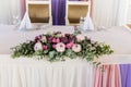 Beautiful pink and creamy flowers on table of newlyweds at wedding reception in restaurant, free space. Wedding table decorated wi