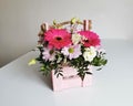 Beautiful pink flower box with gerberas, eustoma, chrysanthemums, pistachios, gypsophila on a white table. Minimalist Royalty Free Stock Photo