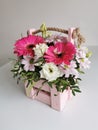 Beautiful pink flower box with gerberas, eustoma, chrysanthemums, pistachios, gypsophila on a white table. Minimalist Royalty Free Stock Photo