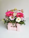 Beautiful pink flower box with gerberas, eustoma, chrysanthemums, pistachios, gypsophila on a white table. Minimalist Royalty Free Stock Photo