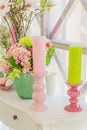 Beautiful pink flowers in green vase and Candles on white wooden commode