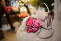 Beautiful pink flowers near the stylish handbag on the table Royalty Free Stock Photo