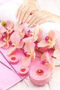 Beautiful pink manicure with orchid, candle and towel on the white wooden table. Royalty Free Stock Photo