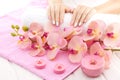 Beautiful pink manicure with orchid, candle and towel on the white wooden table. Royalty Free Stock Photo