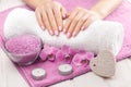 Beautiful pink manicure with orchid, candle and towel on the white wooden table. Royalty Free Stock Photo