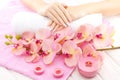 Beautiful pink manicure with orchid, candle and towel on the white wooden table. Royalty Free Stock Photo