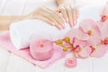 Beautiful pink manicure with orchid, candle and towel on the white wooden table. Royalty Free Stock Photo