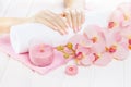 Beautiful pink manicure with orchid, candle and towel on the white wooden table. Royalty Free Stock Photo