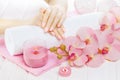 Beautiful pink manicure with orchid, candle and towel on the white wooden table. Royalty Free Stock Photo