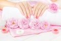 Beautiful pink manicure with tea rose on the white wooden table. spa