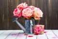 Beautiful pink rose in a tin watering can on wooden background Royalty Free Stock Photo