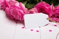 Beautiful pink roses and empty paper card on the white wooden ta Royalty Free Stock Photo