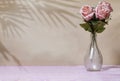 Beautiful pink roses in vase on color background with palm leaves shadow. Royalty Free Stock Photo