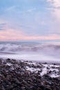 Beautiful sea landscape. Beautiful pink sunset sky over sea coast with pebble beach. Photo is frozen using long shutter speed