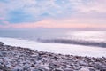 Beautiful sea landscape. Beautiful pink sunset sky over sea coast with pebble beach. Photo is frozen using long shutter speed