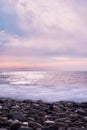Beautiful sea landscape. Beautiful pink sunset sky over sea coast with pebble beach. Photo is frozen using long shutter speed