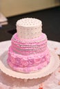 Beautiful pink three-tiered wedding cake on table
