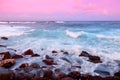 Beautiful pink tinted waves breaking on a rocky beach at sunrise on east coast of Big Island of Hawaii Royalty Free Stock Photo