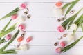 Beautiful pink tulips with colorful quail and chicken eggs in nest on white wooden background. Royalty Free Stock Photo