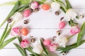 Beautiful pink tulips with colorful quail and chicken eggs in nest on white wooden background. Royalty Free Stock Photo