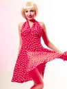 Beautiful pinup girl in blond wig and retro red dress dancing. Party. Royalty Free Stock Photo