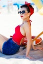 Beautiful pinup sitting on sand under umbrella Royalty Free Stock Photo